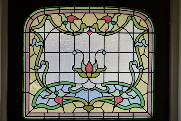 Cette imposte importante domine une porte en bois verni très Art nouveau.