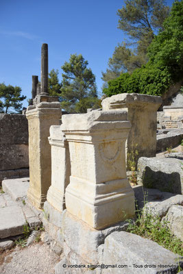 [NU923-2022-3854] Glanum : Sanctuaire - Petits autels posés devant la chapelle d'Hercule - en arrière-plan, colonnes du temple de Valetudo