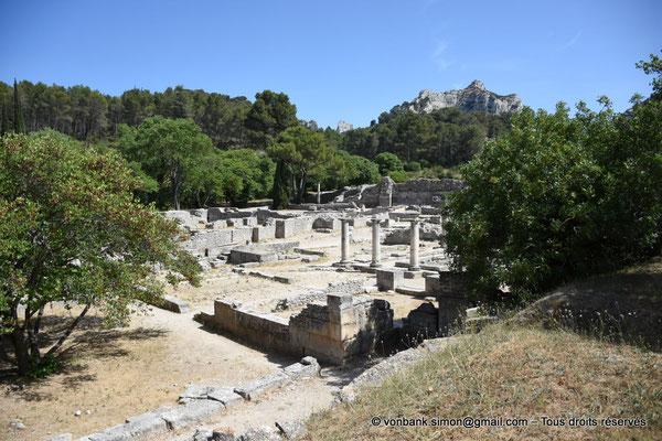 [NU923-2022-3787] Glanum : Maison des Antes - sur la droite, le portique (vue partielle) - en arrière-plan, les thermes puis la colonne dorico-toscane située à l'Est de la Curie