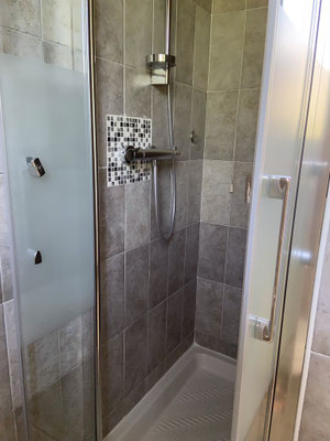 Eine Dusche mit einer gläsernen Tür und einem modernen Duschkopf.