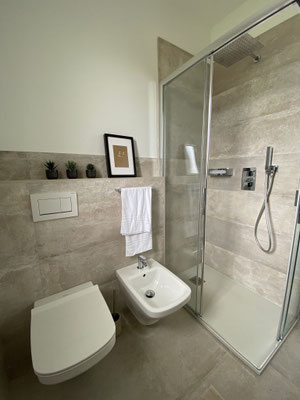 Badezimmer mit Dusche und Toilette, hell und modern eingerichtet.