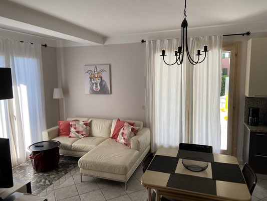 Gemütliches Wohnzimmer mit Couch, Tisch und Stühlen im eleganten Design.