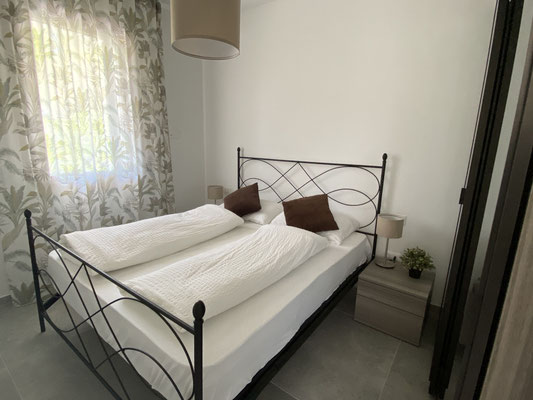 Schlafzimmer in Villa Costanza mit einem weißen Bett und einem Fenster, das Tageslicht hereinlässt.