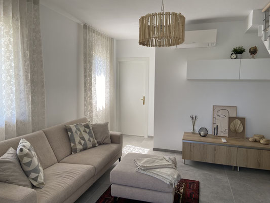 Gemütliches Wohnzimmer mit Couch, Tisch und Stehlampe.