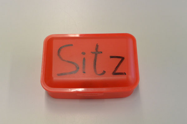 Eine Brotdose mit der Aufschrift "Sitz". Zeigt man Blade die Box, setzt er sich hin. 