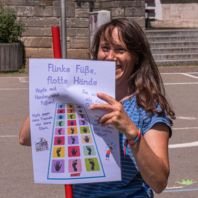 Eine Lehrerin hält das Schild ihrer Station hoch, um sie zu erklären.