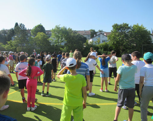 Alle Teilnehmer wärmen sich gemeinsam auf dem Sportplatz auf.