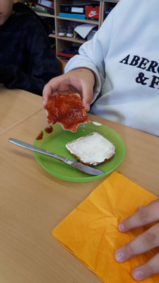 Ein Kind hält eine Scheibe Dinkelbrot mit Marmelade in der Hand.