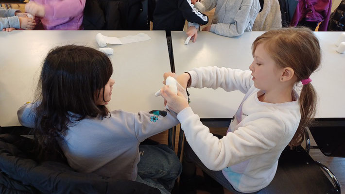 Ein Kind verbindet einen Arm eines anderen Kindes.