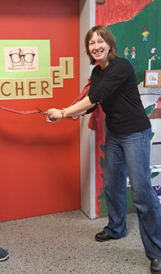 Die Schulleiterin durchschneidet ein rotes Band zur Eröffnung der Schülerbücherei.