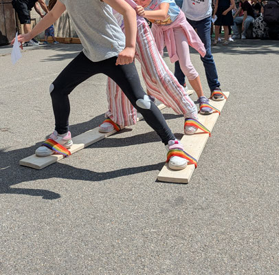 SchülerInnen spielen Gruppenlanglauf auf zwei langen Skibrettern.