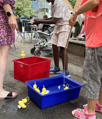 Kinder angeln Plastikenten aus einer Wanne mit Wasser.