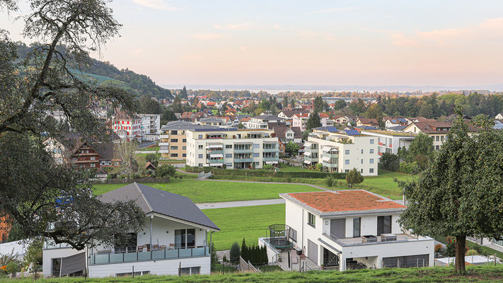 Blick zum Wohnerlebnis SunneThal und zum Bodensee. Auf den Dächern befinden sich Solaranlagen. Die Balkonbrüstungen aus satiniertem Glas sind lichtdurchlässig und dienen als Wind- und Sichtschutz