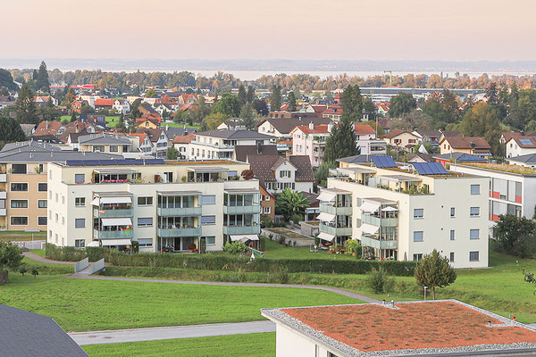 Blick zum Wohnerlebnis SunneThal und zum Bodensee. Auf den Dächern befinden sich Solaranlagen. Die Balkonbrüstungen aus satiniertem Glas sind lichtdurchlässig und dienen als Wind- und Sichtschutz