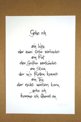 Vollansicht Kalligrafie „Gehe ich“ Tusche auf Papier vor Hintergrund einer Tischplatte