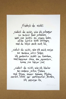 Vollansicht Kalligrafie „Siehst du nicht“ Tusche auf Papier vor Hintergrund einer Tischplatte
