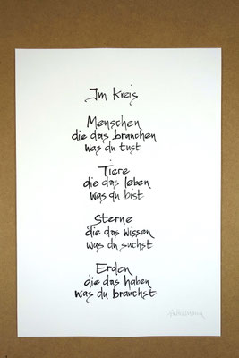 Vollansicht Kalligrafie „Im Kreis“ Tusche auf Papier vor Hintergrund einer Tischplatte