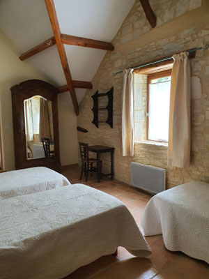 A l'étage, une première chambre de notre gîte très haut de plafond avec ses poutres et murs en pierre et sa fenêtre