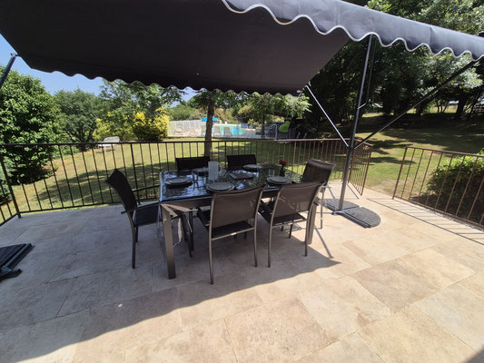 Vue de l'entrée du gîte, notre grande terrasse avec sa table, chaises et auvent ouvert