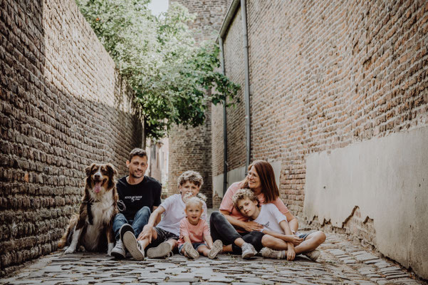 Familie mit Hund sitzt in einer Kopfsteinpflastergasse