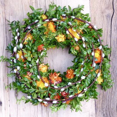 Buchsbaumkranz mit Weidenkätzchen und orangenen Strohblumen