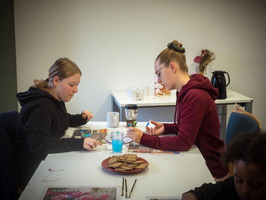 2 Mädchen sitzen am Tisch und bemalen Herzen 