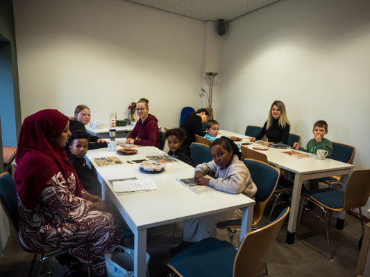 Kinder sitzen am Tisch und bemalen Herzen 