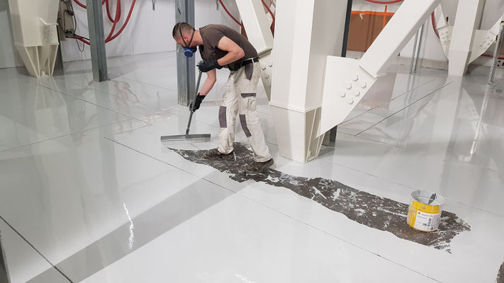 homme appliquant un revêtement sur un sol en béton