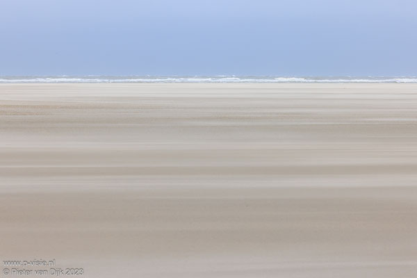 Het zand waait over het strand