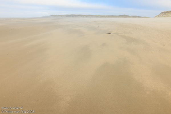 Het zand waait over het strand