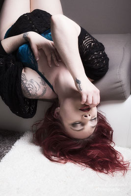 femme rouge tatoutée en lingerie sur un canapé
