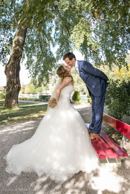 Bräutigam küsst Braut auf einer Bank im Schadaupark, Schloss Schadau, Thun