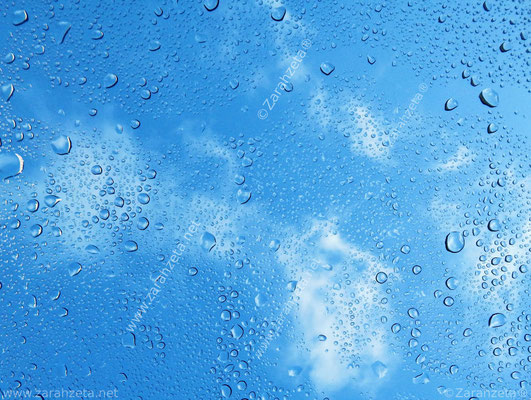 Regentropfen auf Glasscheibe mit blauem Himmel als Hintergrund