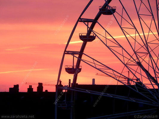 Riesenrad vor Stadtsilhouette in der Morgenröte