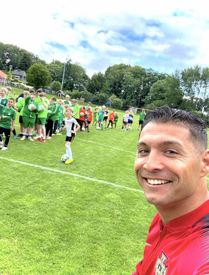 Selfie von Fußball-Freestyler Saki mit wartenden Kindern auf dem Fußballplatz beim SV GW Kleinenkneten
