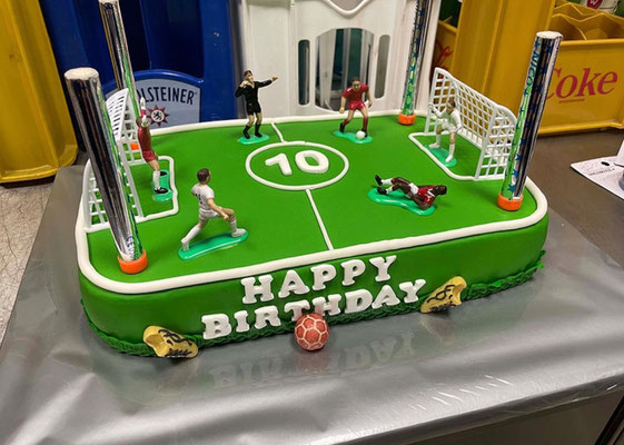 Green birthday cake decorated with football pitch and goalposts