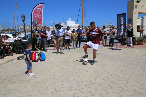 Kinder schauen zu: Saki präsentiert Fußball-Freestyle beim Gżira United FC Event an der Marina auf Malta.