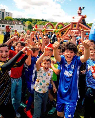 Group of kids celebrating with raised hands during football birthday event