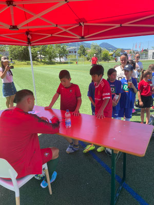 Kinder stehen unter rotem Pavillon an einem Tisch bei Fußball-Event des 1. FC Lachen Altendorf