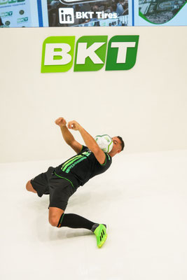 Fußball Freestyler Saki bei einem Bodentrick vor dem BKT-Logo auf der Messe in Hannover