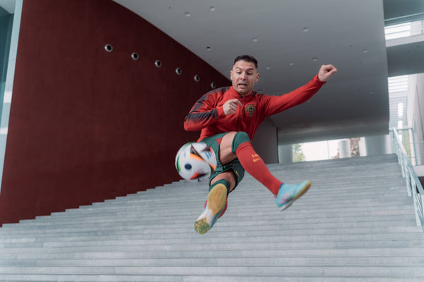 Fußball-Freestyler Saki springt im roten Portugal-Outfit mit Ball auf einer breiten Treppe im Bundeskanzleramt