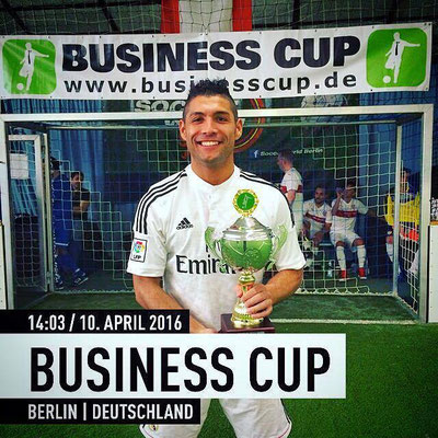 Saki hält den Pokal beim Business Cup Berlin – Porträt vor Business-Cup-Banner.
