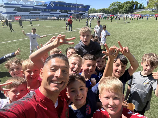 Selfie von Saki mit Kindern auf einem Fußballfeld bei einem REWE-Event im Stadionumfeld