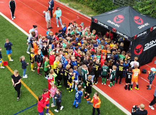 Large group of children gathered at athletics track for football birthday games