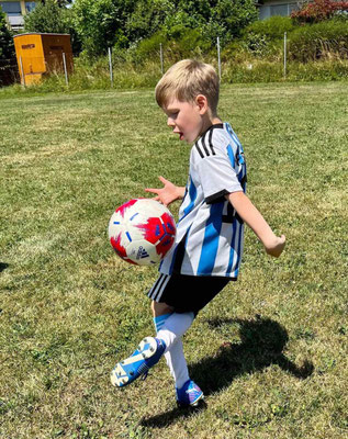 Young boy dribbling football during birthday training session outdoors