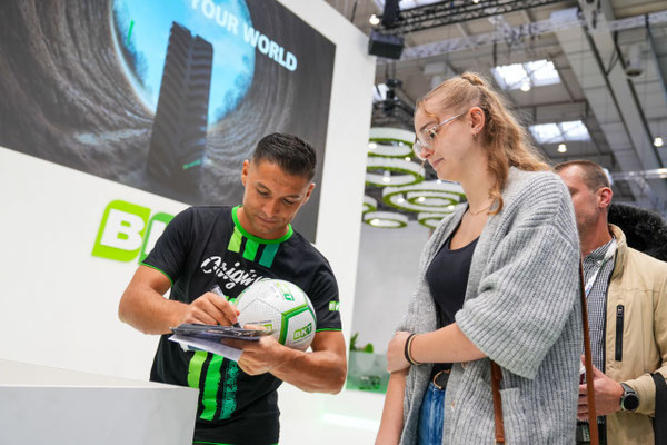 Saki gibt einer Messebesucherin ein Autogramm am BKT-Stand auf der Agritechnica 2025