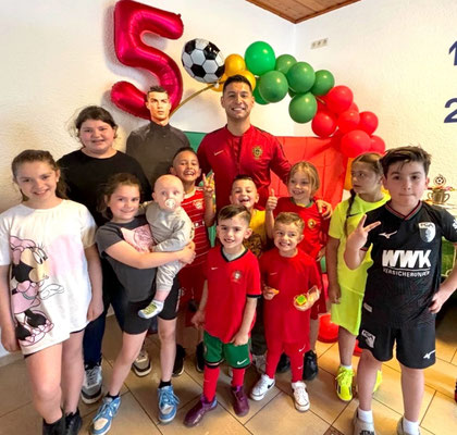 Children's indoor group photo with footballs and coach after training session