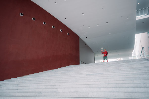 Saki am oberen Ende einer breiten Treppe im modernen Innenbereich des Bundeskanzleramts in Berlin