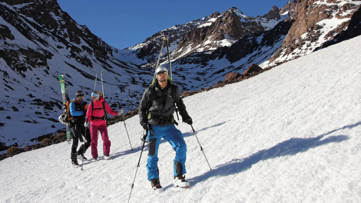 Mit Steigeisen und Ski am Rucksack machen wir uns auf zur letzten Skitour unserer Reise nach Marokko