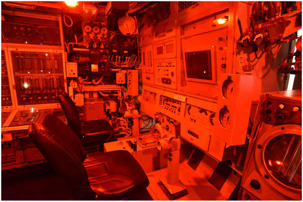 Postes de commande. La salle est ici en "mode nuit", cette lumière rouge qui permet à l'équipage de garder un repère entre le jour et la nuit pendant des missions durant de 55 à 75 jours.